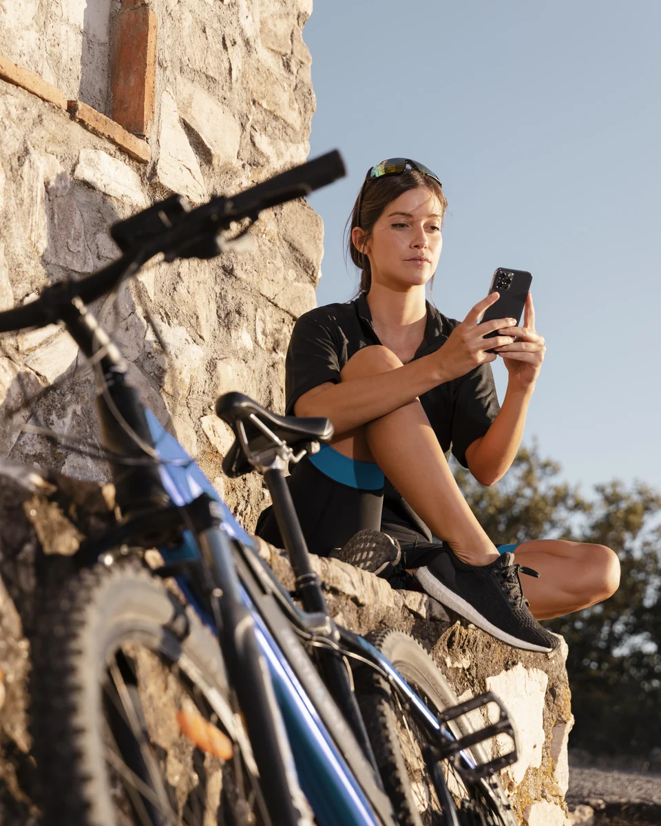 A rider resting on a stone wall next to her electric bike